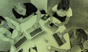 Sfeerbeeld van collega's die samenwerken met laptops aan een ronde tafel.